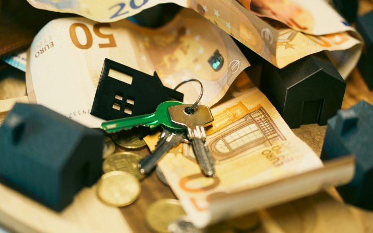 Chiavi di casa sopra a banconote e monete 