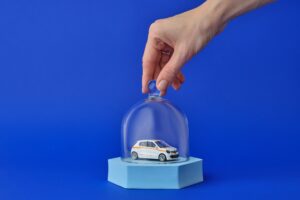 Auto giocattolo dentro ad una bolla di vetro su sfondo blu: concetto di assicurazione