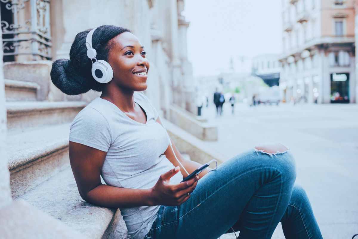 Ragazza sorridente ascolta musica in strada