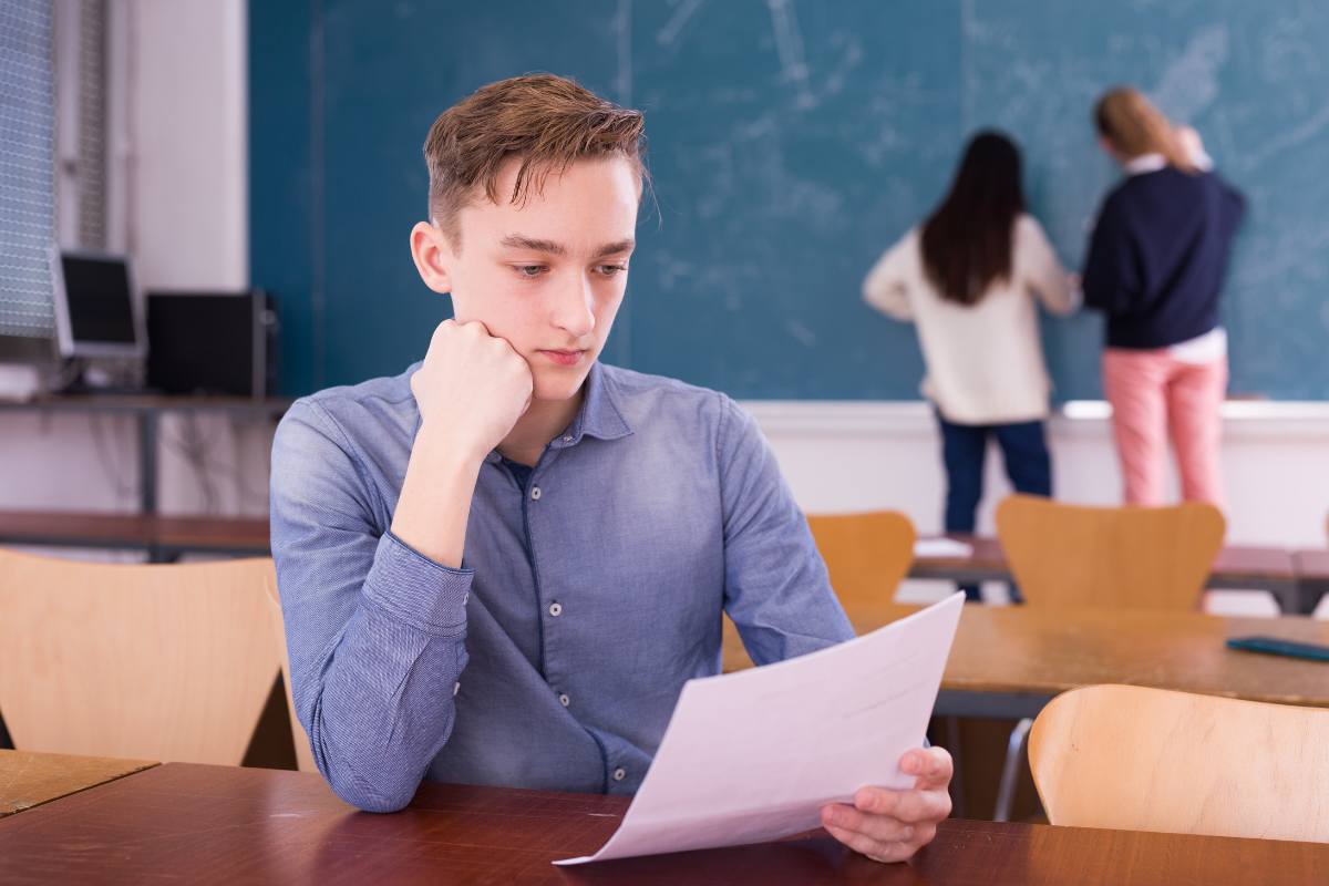 ragazzo guarda sconsolato un compito a scuola