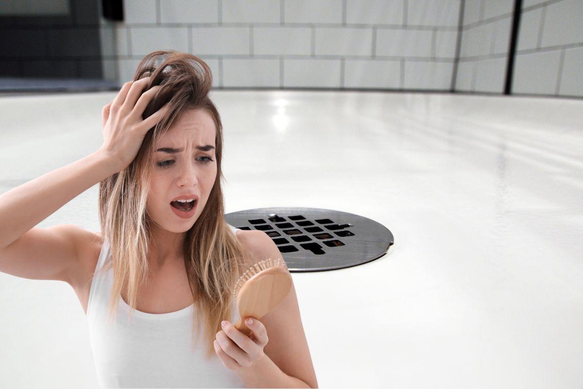 donna che guarda spazzola piena di capelli e scarico della doccia