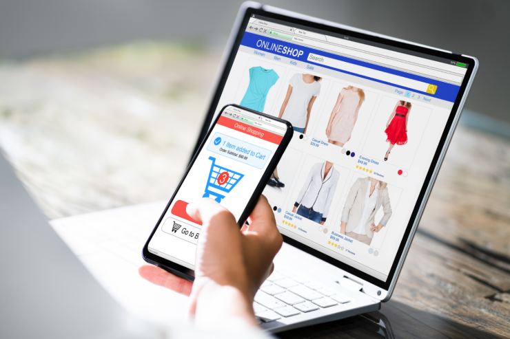 uomo di fronte e pc fa acquisti con il cellulare
