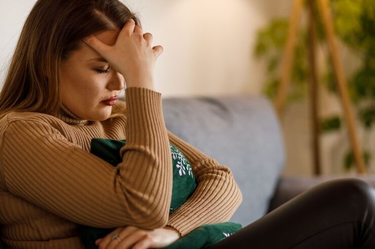 Ragazza con mano sulla fronte, triste