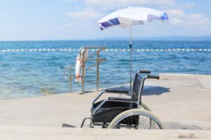 carrozzella disabile in spiaggia di fronte a ombrellone e al mare