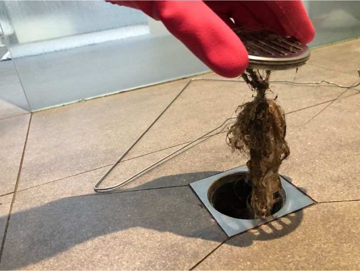 mano che tira capelli dallo scarico della doccia